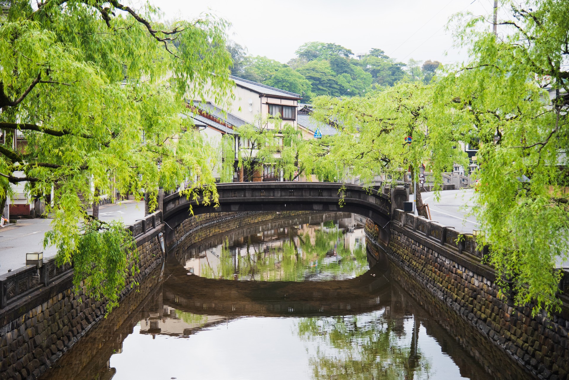 Canal view spring season in Kinosaki Onsen village, Toyooka City, Hyogo, Japan. Landscape city view. Tree beside canal with reflect in water near the bridge. Japan traveler trip.